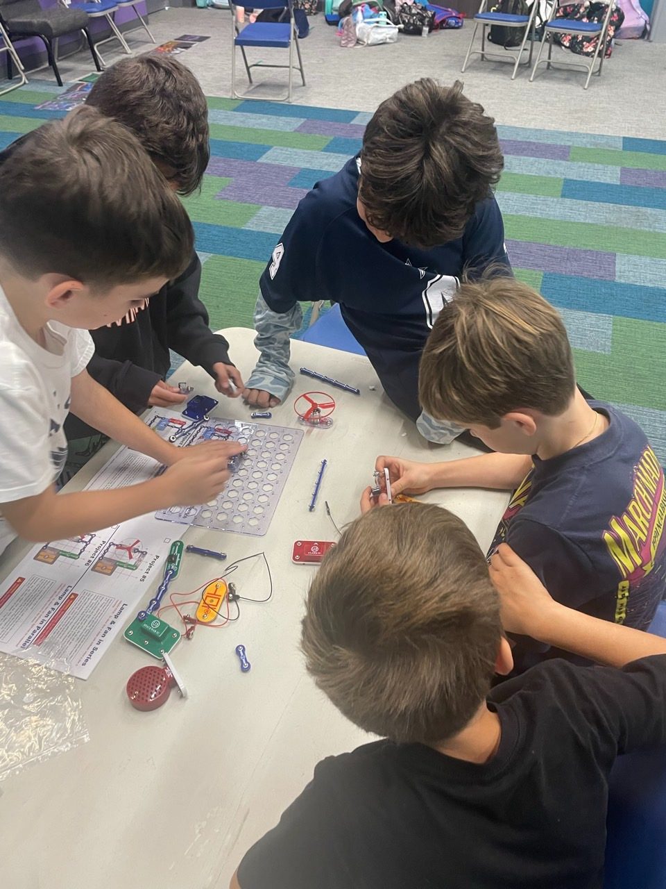 Students building an electric circuit kit together at a table