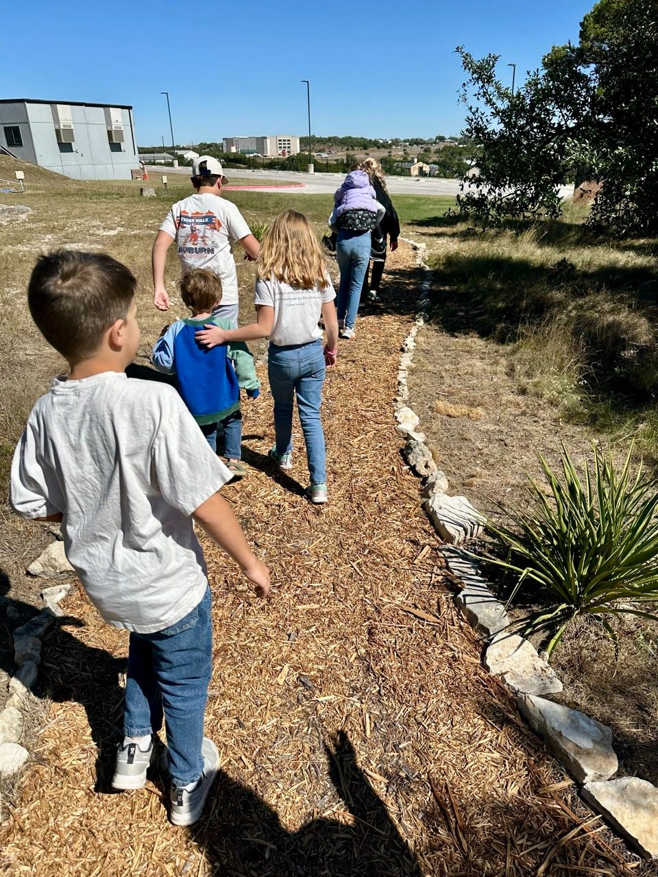 Children walking together along a mulched nature path